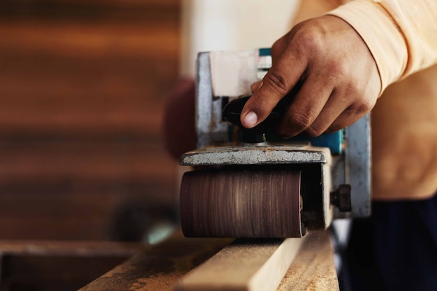 A carpenter is sanding the wood with a sandpaper.