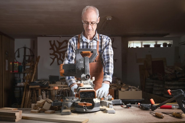 Carpenter is sawing a wood plank with electric circular saw machine in carpentry workshop Workwood DIY concept High quality photography