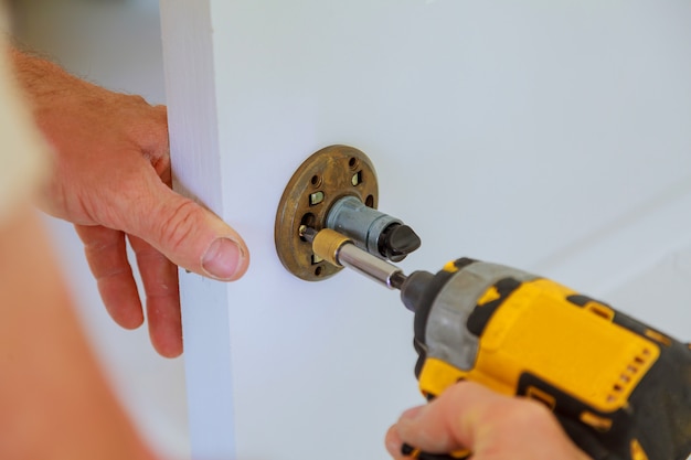 Carpenter lock installation with electric drill into interior wood door