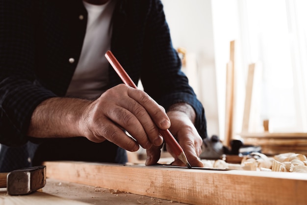 Il carpentiere fa segni a matita su una tavola di legno