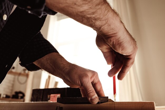 Carpenter makes pencil marks on a wood plank