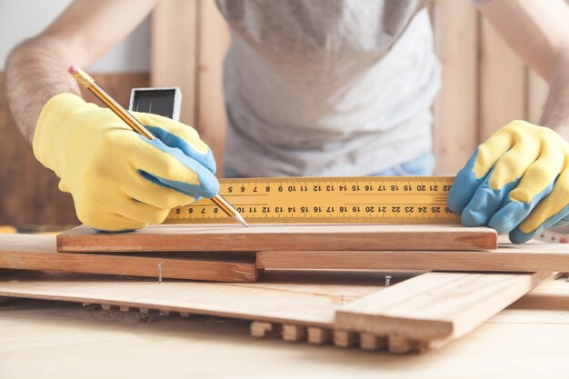Carpenter making marks on wooden plank with a pencil