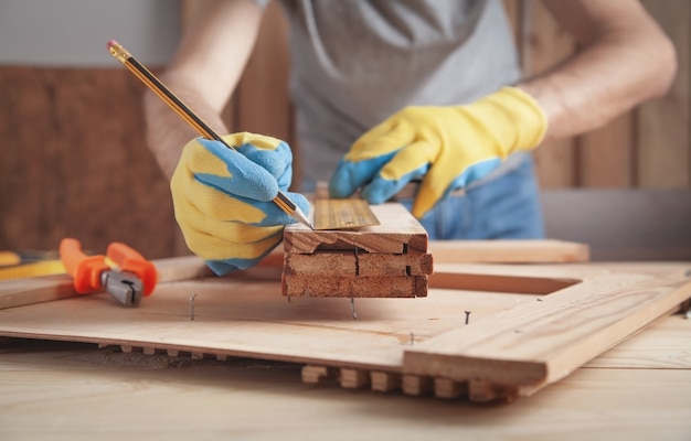 Carpentiere che fa i segni sulla plancia di legno con una matita.