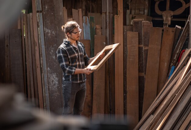 Carpenter man holding window frame wooden standing at the carpentry workshop