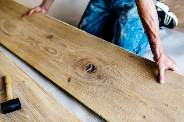 Uomo del carpentiere che installa pavimento di legno