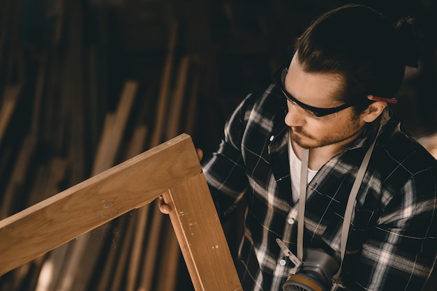 Foto falegname professionista esperto nella lavorazione del legno guardando i dettagli del capolavoro del legno nel laboratorio di mobili