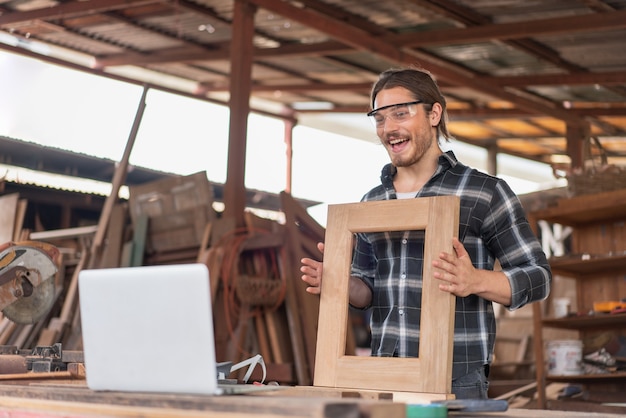 Carpenter man selling window frame wooden online at the carpentry workshop.Sell stuff online