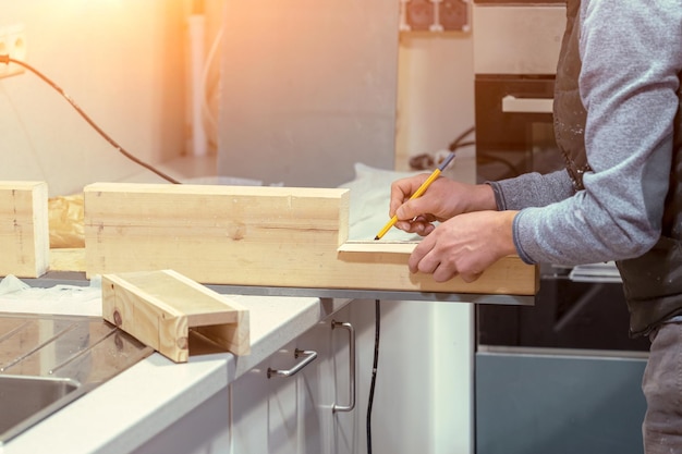 The carpenter marks the dimensions on the board for further cutting closeup of the carpenter's hands