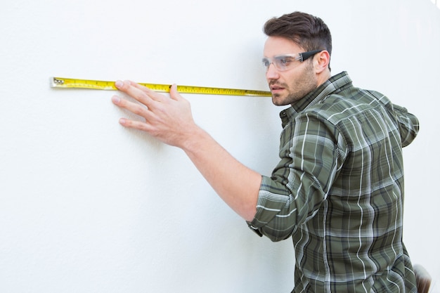 Carpenter measuging white wall