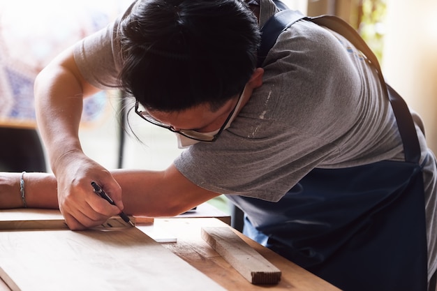 大工が板を測定して部品を組み立て、顧客のために木製のテーブルを作ります