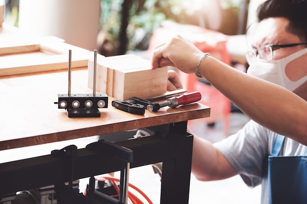 A carpenter measures the planks to assemble the parts, and build a wooden table for the customer