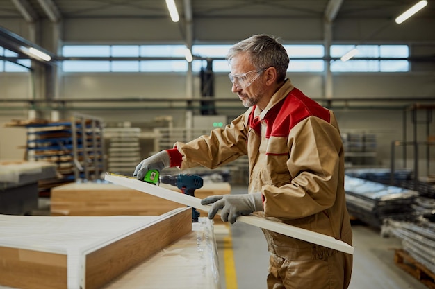 Carpenter measuring plank with tape measure in a workshop