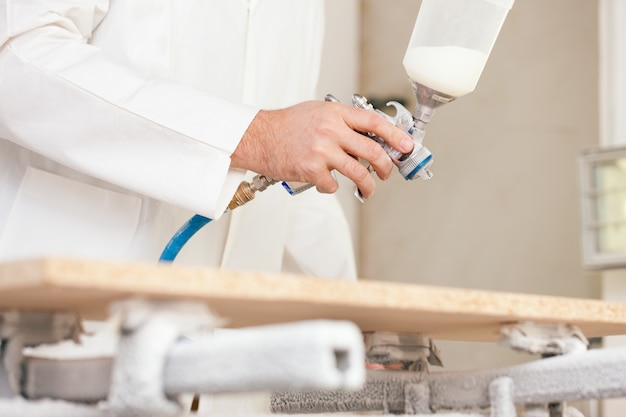 Carpenter painting wood with airbrush