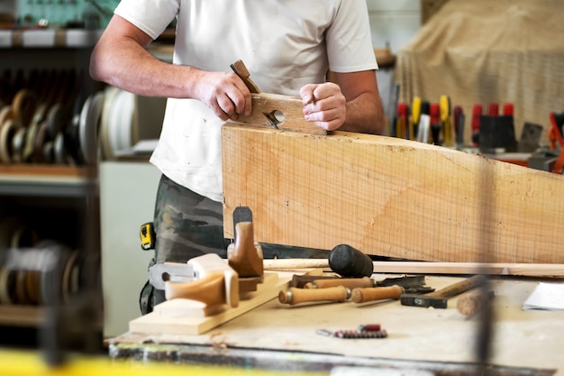 Carpenter planing a wooden block with a planer