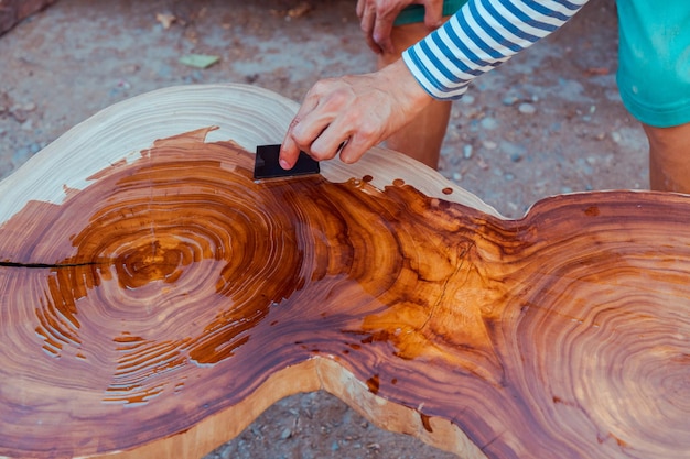 Carpenter pouring linseed oil on a wooden table