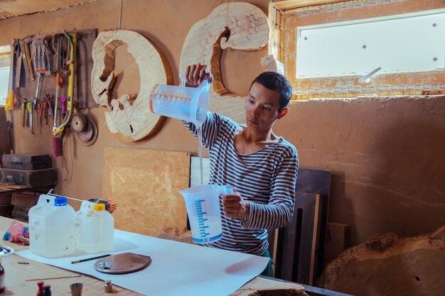 Carpenter preparing epoxy resin for woodworking and carpentry production