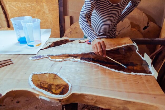 Carpenter removing air bubbles from epoxy table