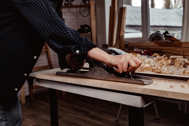 Foto le mani del falegname piallano una tavola di legno con una pialla a mano