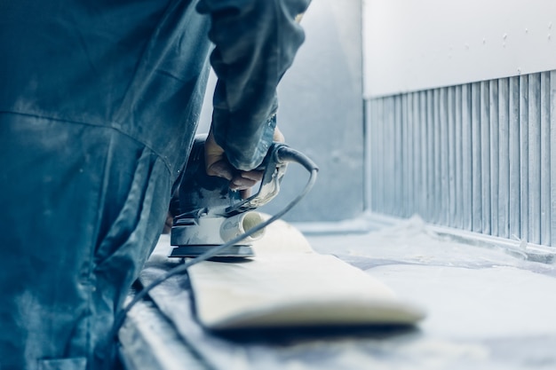 Carpenter sanding a board with an electric sander