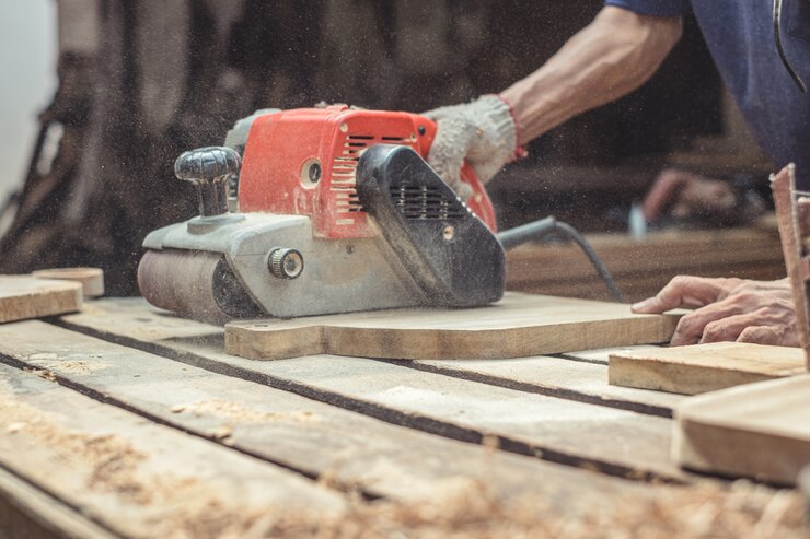 Photo carpenter sanding wood with belt sander at workshop in wooden cutting board project or woodworking carpentry