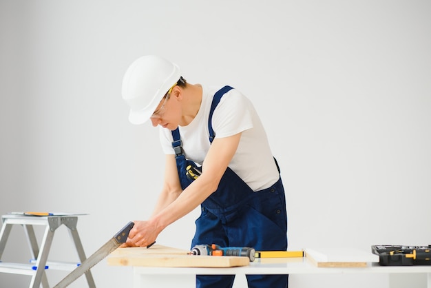Carpenter sawing white board during apartment renovating