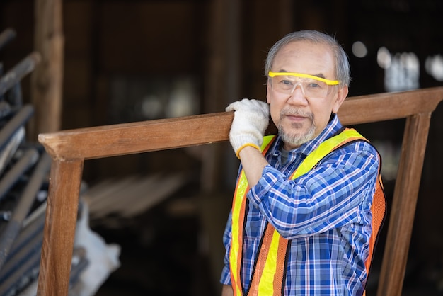 Carpenter, Senior man sanding wooden fence in workplace using work tool