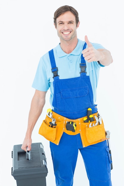 Photo carpenter showing thumbs up sign while carrying tool box