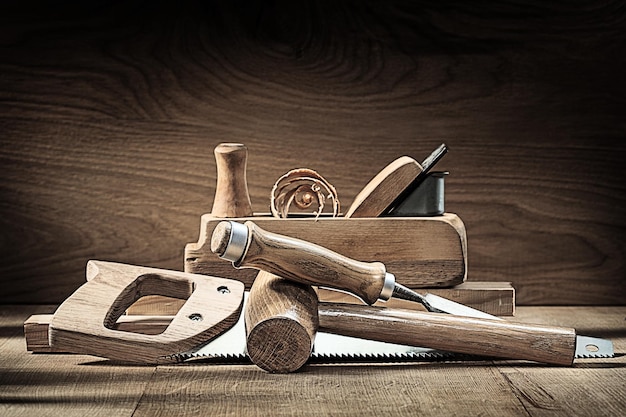 Carpenter tools woodworkers plane wooden mallet chisel handsaw on vintage wooden background