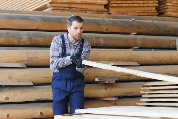 Carpenter in uniform check boards on sawmill