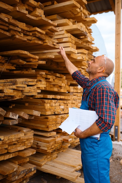 Carpenter in uniform check boards on sawmill