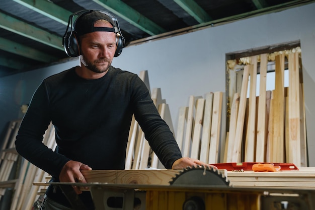 Photo a carpenter uses an electric chopper to prepare boards for the manufacture of wood products