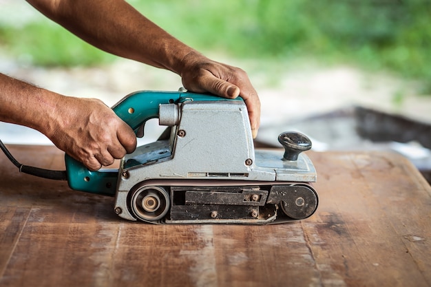 The carpenter uses power sander as a powerful tool in wood finishing. 