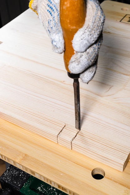 Carpenter using chisel cuts groove on wooden board