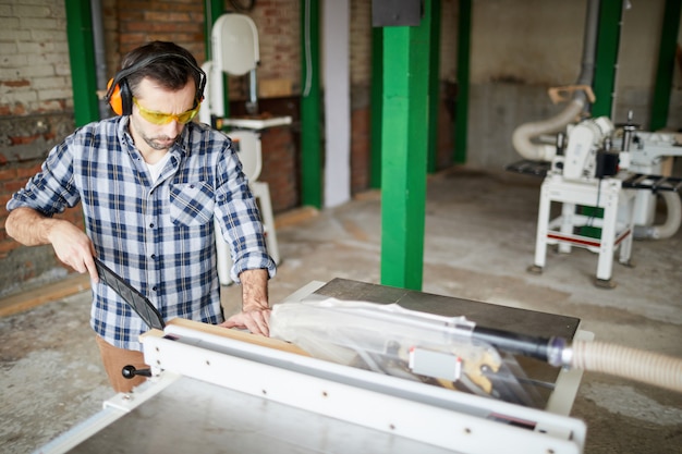 Carpenter using cutting table in workshop