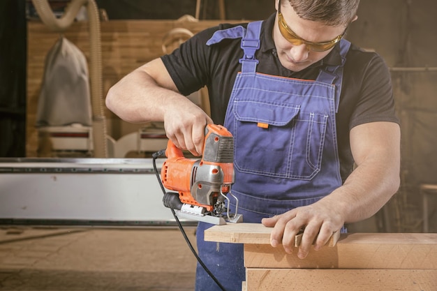 A carpenter using a jigsaw to cut wood cuts bars Home repair concepts close up