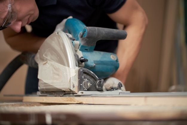 Carpenter in white gloves works on a jigsaw