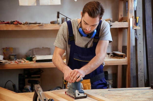 Carpenter with electric sander in workshop