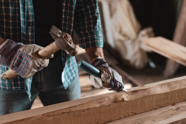 Carpenter with hammer and chisel handles wood.