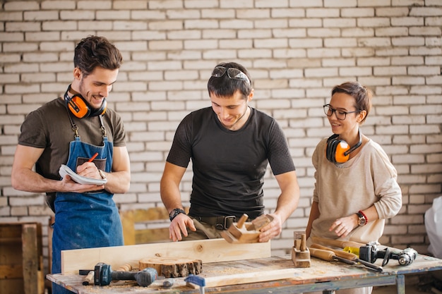 Carpenter with students in woodworking workshop