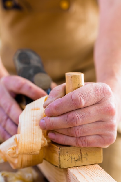 Carpenter with wood planer and workpiece in carpentry