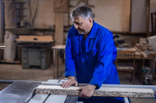 Carpenter at work at his workshop, wood processing on a woodworking machine