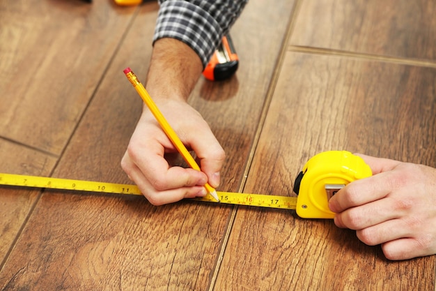 Carpenter worker installing laminate flooring in the room