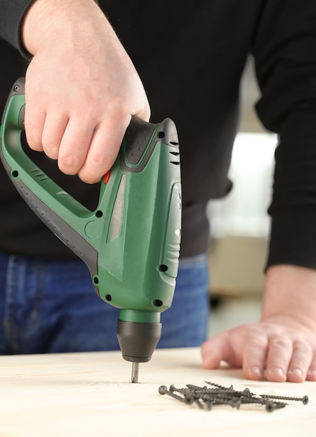 Carpenter working with electric equipment, closeup