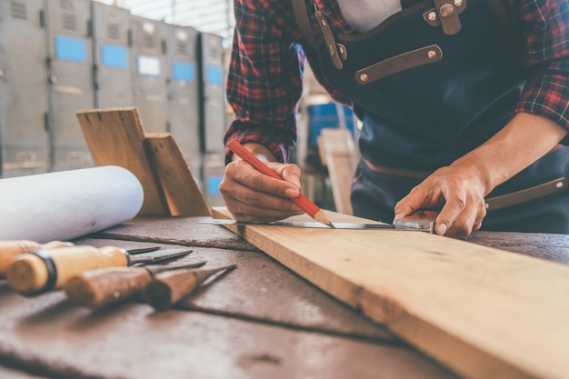 Carpentiere che lavora con l'attrezzatura sulla tavola di legno nel negozio di falegnameria. la donna lavora in una falegnameria.