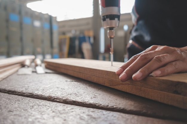大工は、大工店の木製テーブルの機器を操作します。女性は大工店で働いています。