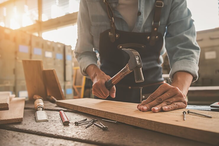 Photo carpenter working with equipment on wooden table in carpentry shop.