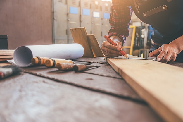 Photo carpenter working with equipment on wooden table in carpentry shop.