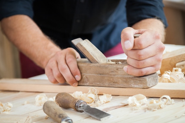 carpenter working  with  plane  on wooden background