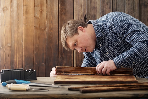 Carpentiere che lavora con gli strumenti sulla parete di legno