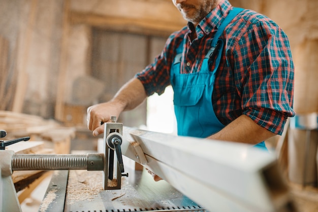 Foto il carpentiere lavora su macchina piana, lavorazione del legno, industria del legname, falegnameria. lavorazione del legno su fabbrica di mobili